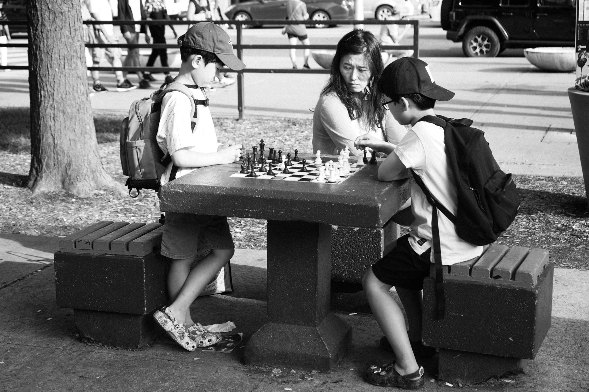 Kids playing chess at a stone table in the park