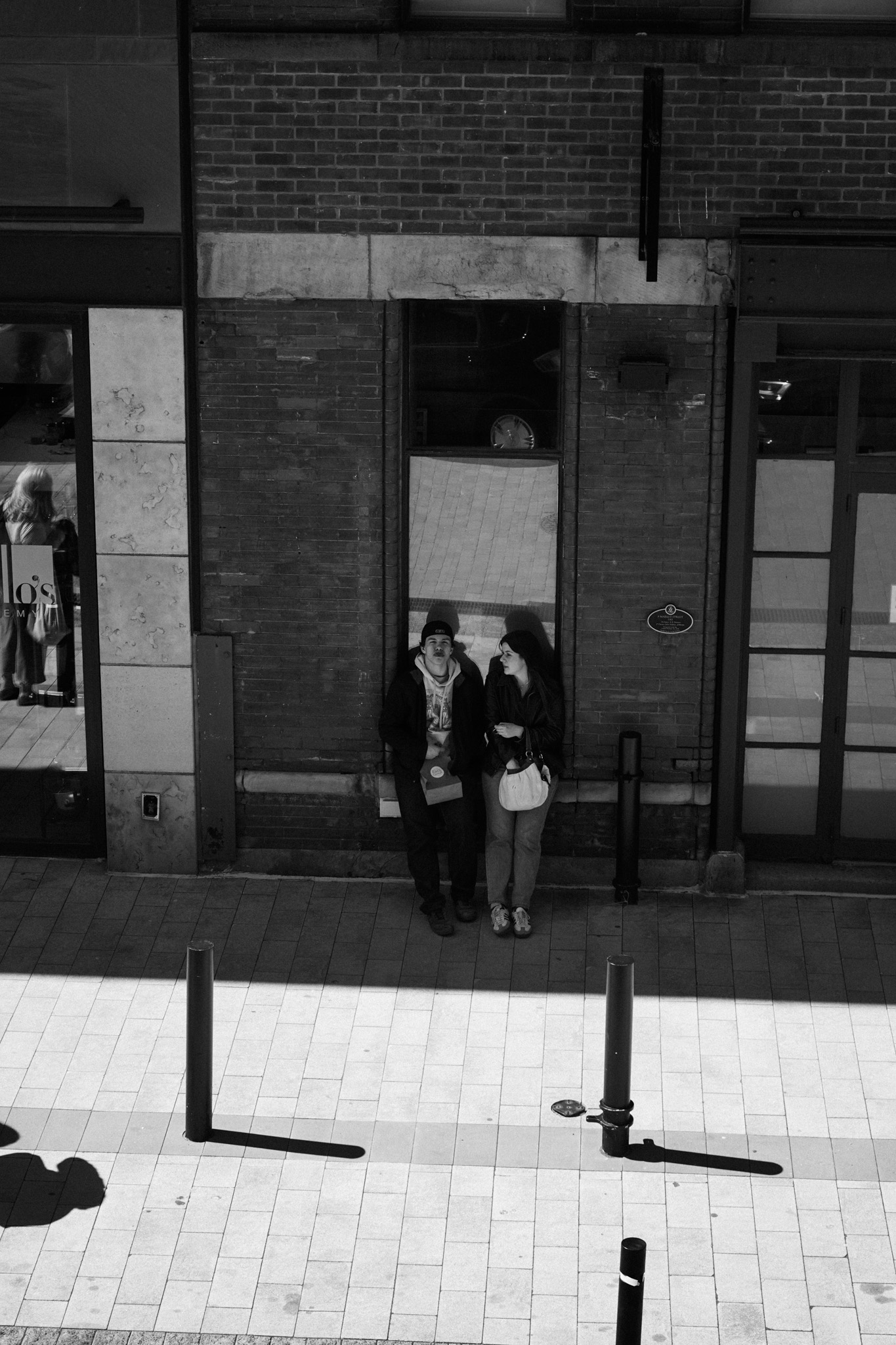 Two people standing close together in a narrow doorway niche on a city street