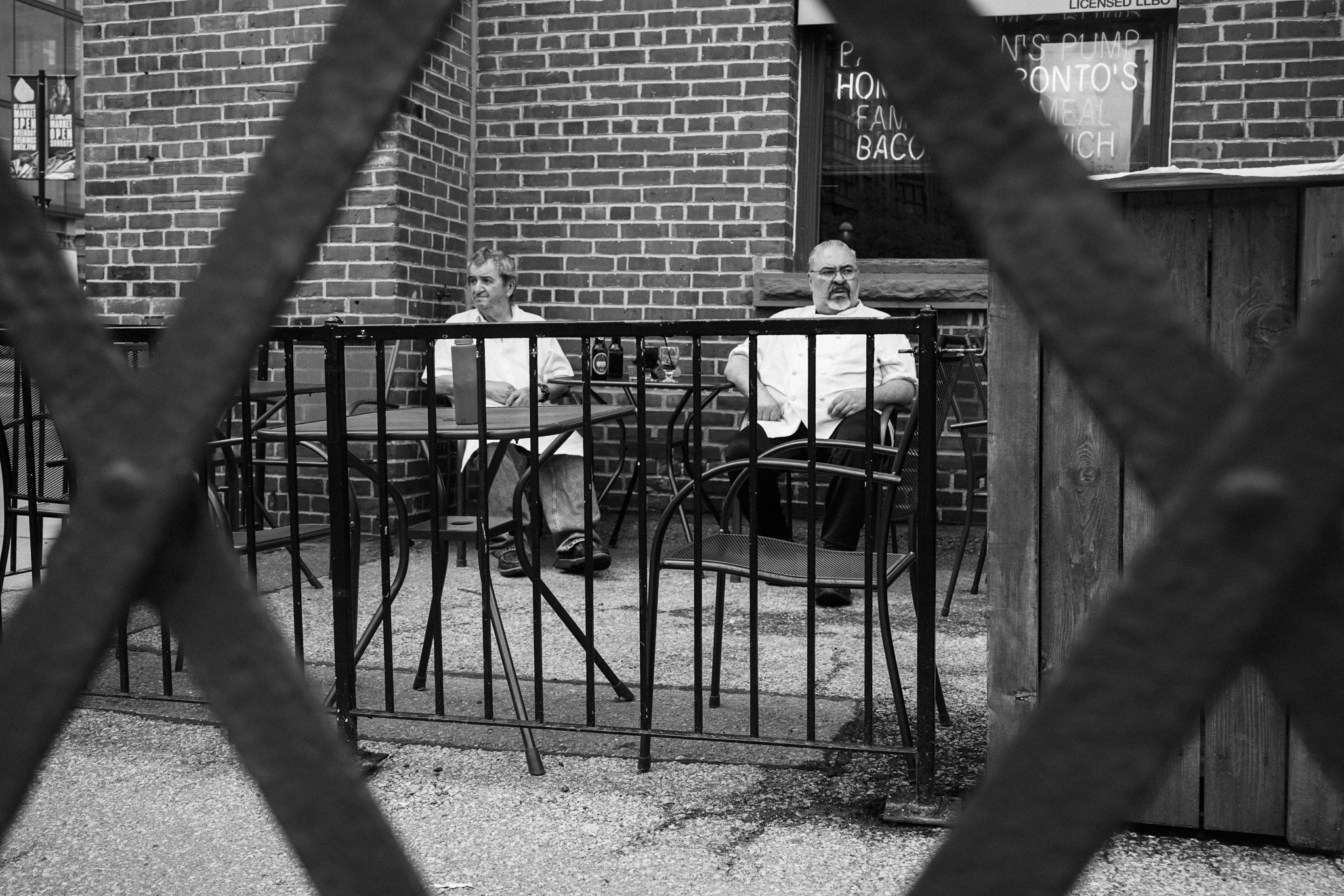 Two people sitting at a patio seen through an iron fence