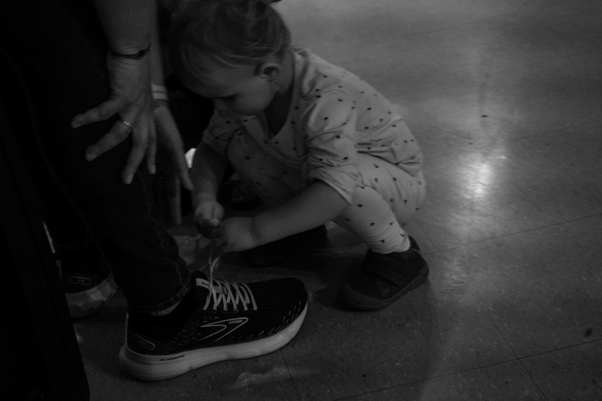Toddler crouching down to touch an adult's shoe