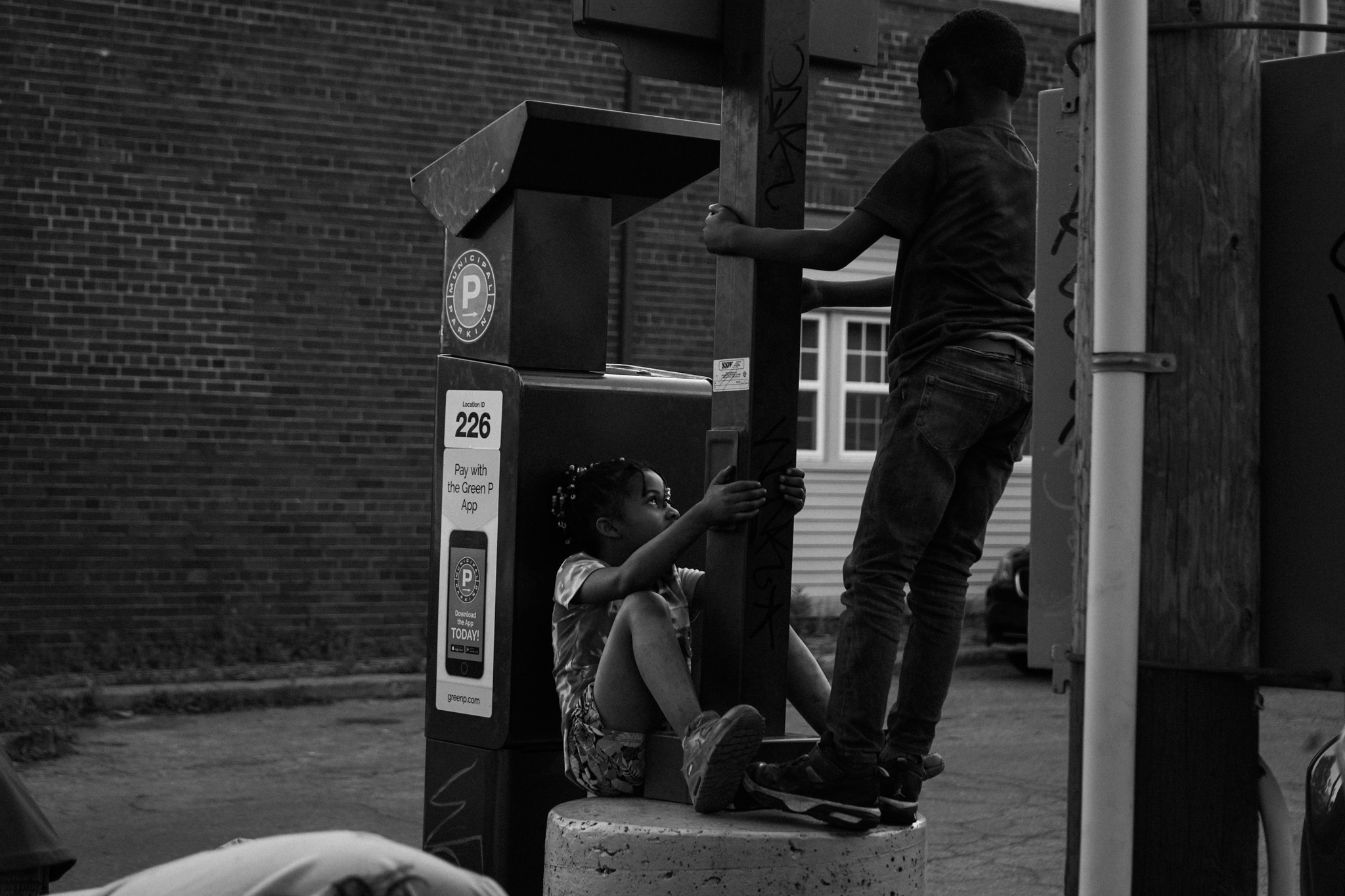 Two children climbing on a parking meter