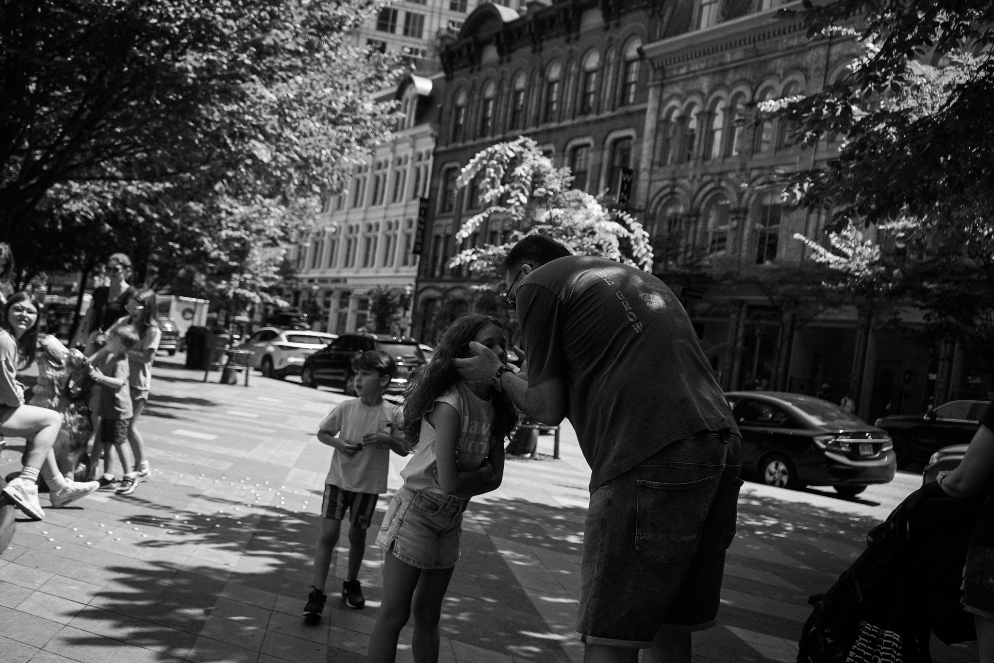 Father bending down to embrace his daughter on a busy street