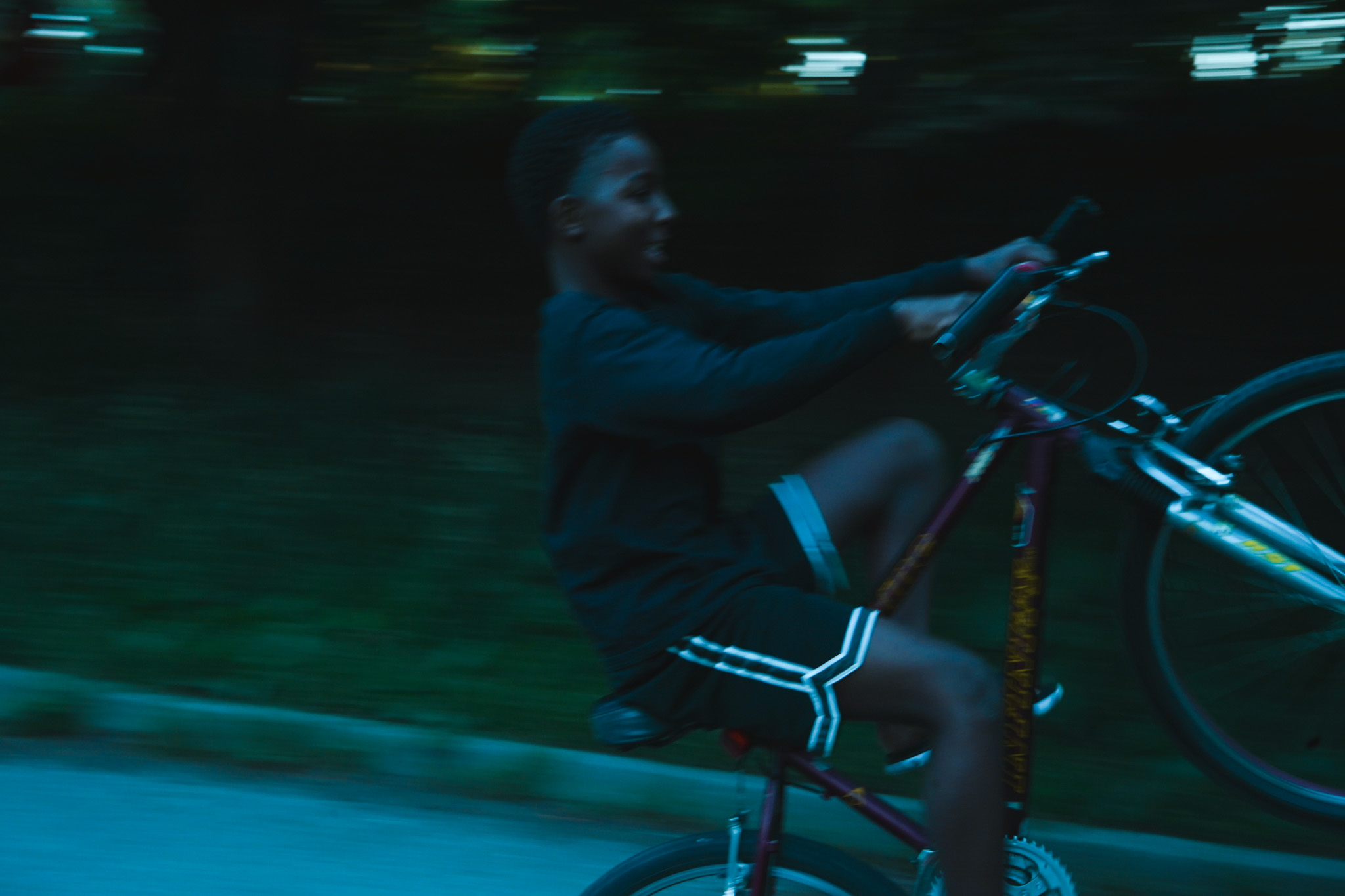 Boy on a bike at night, motion blur dissolving into darkness
