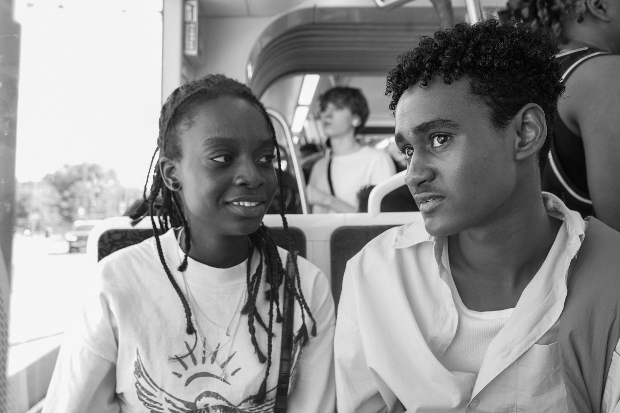 Two young people on the bus, one smiling, catching each other's gaze