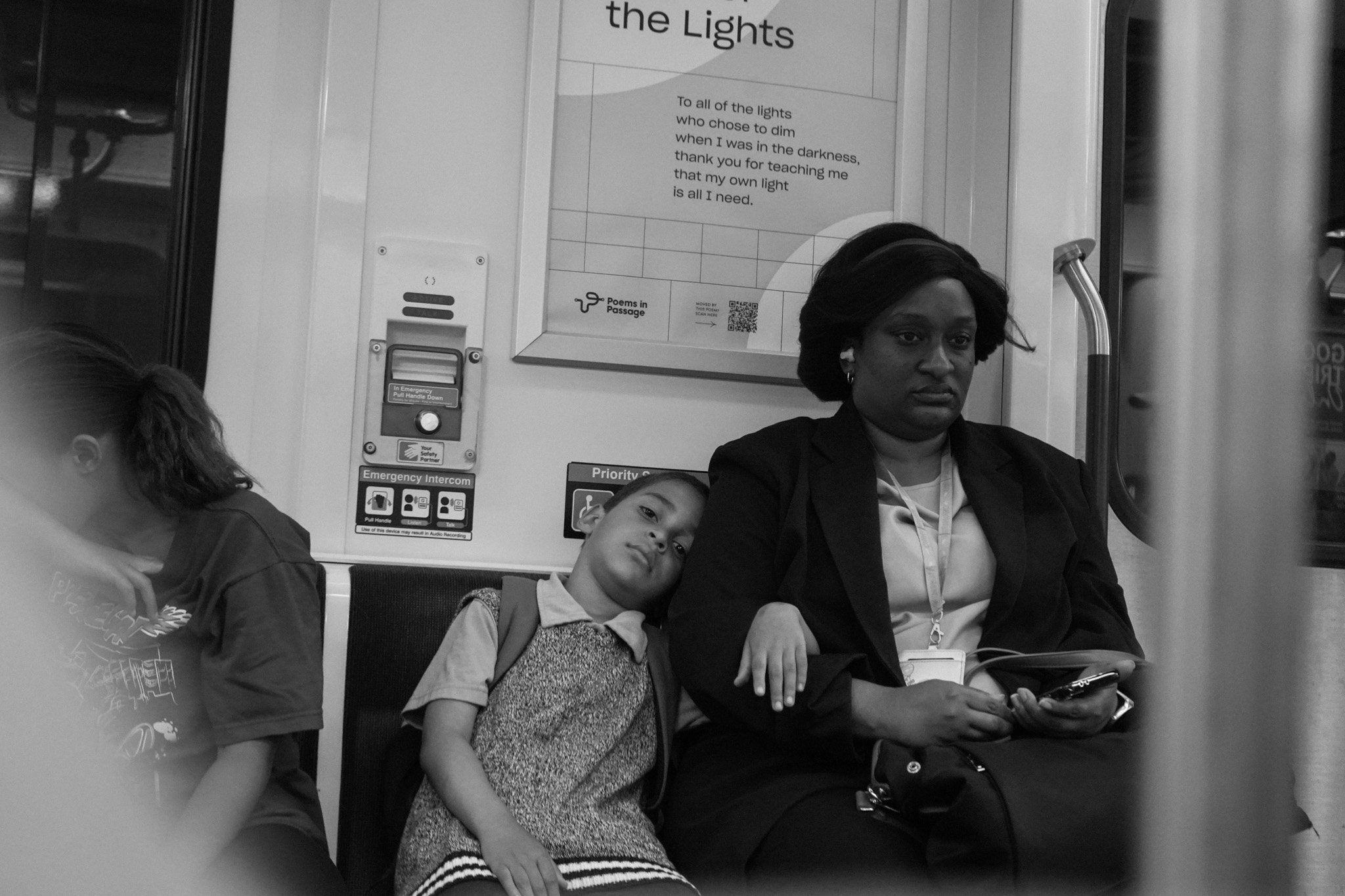 Child leaning against mother beneath a poem poster