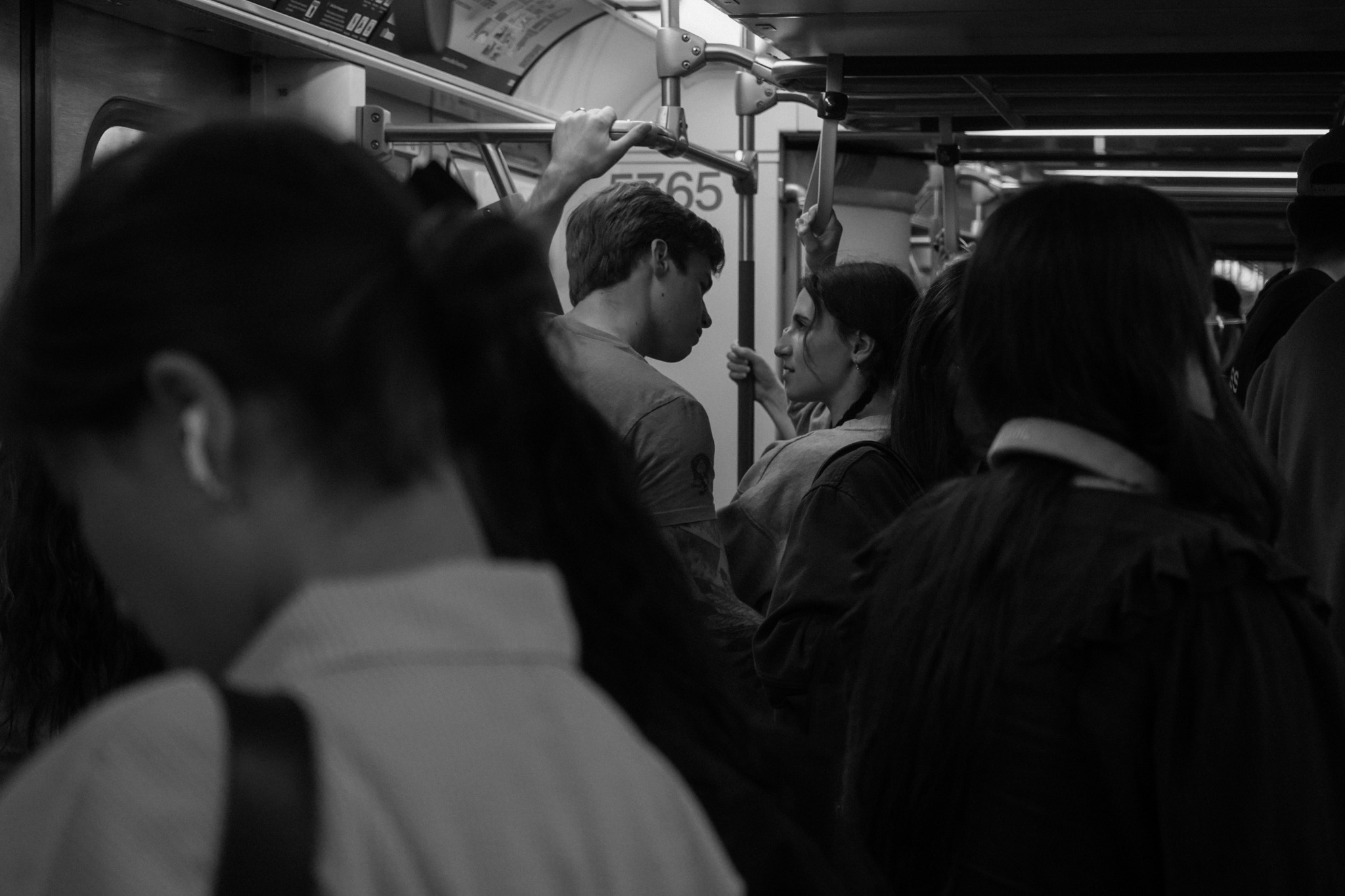 Couple standing close in a crowded carriage, seen through other passengers