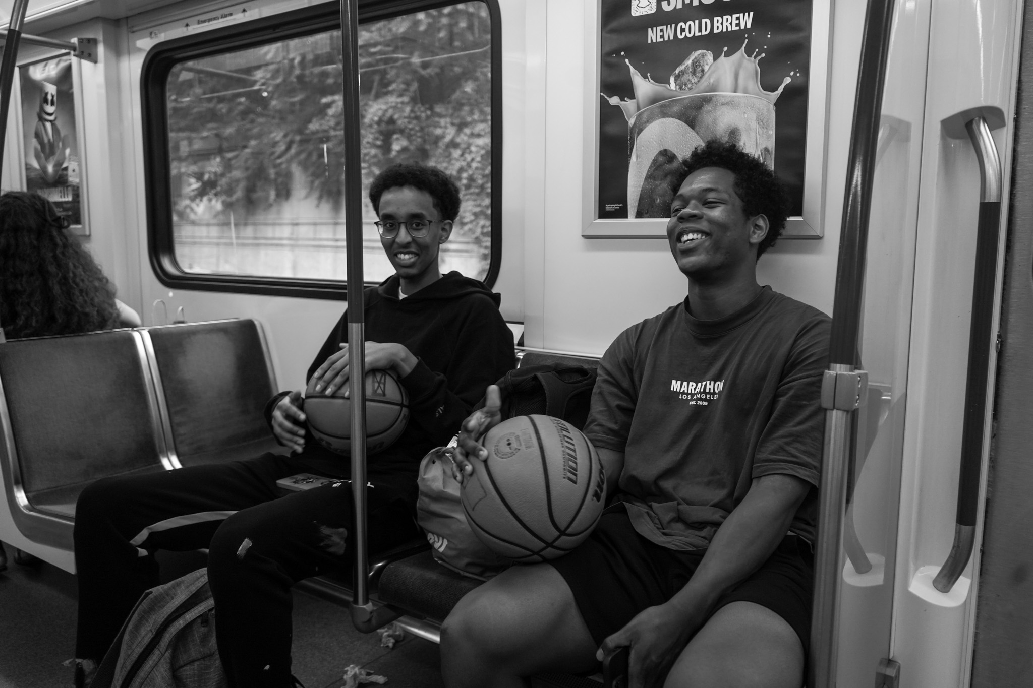 Two young men laughing with basketballs on the train