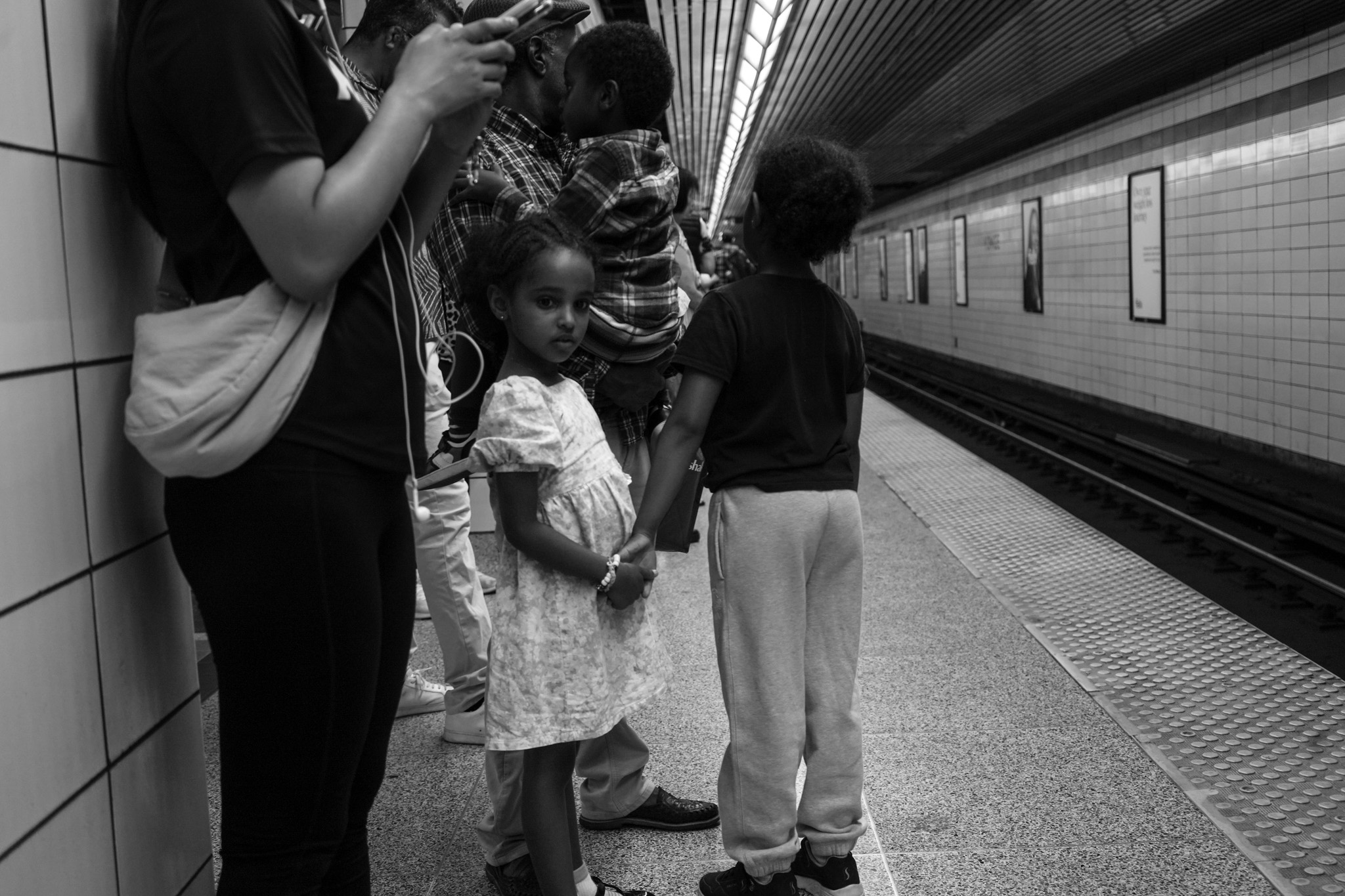 Children waiting on a subway platform, one looking directly at the camera