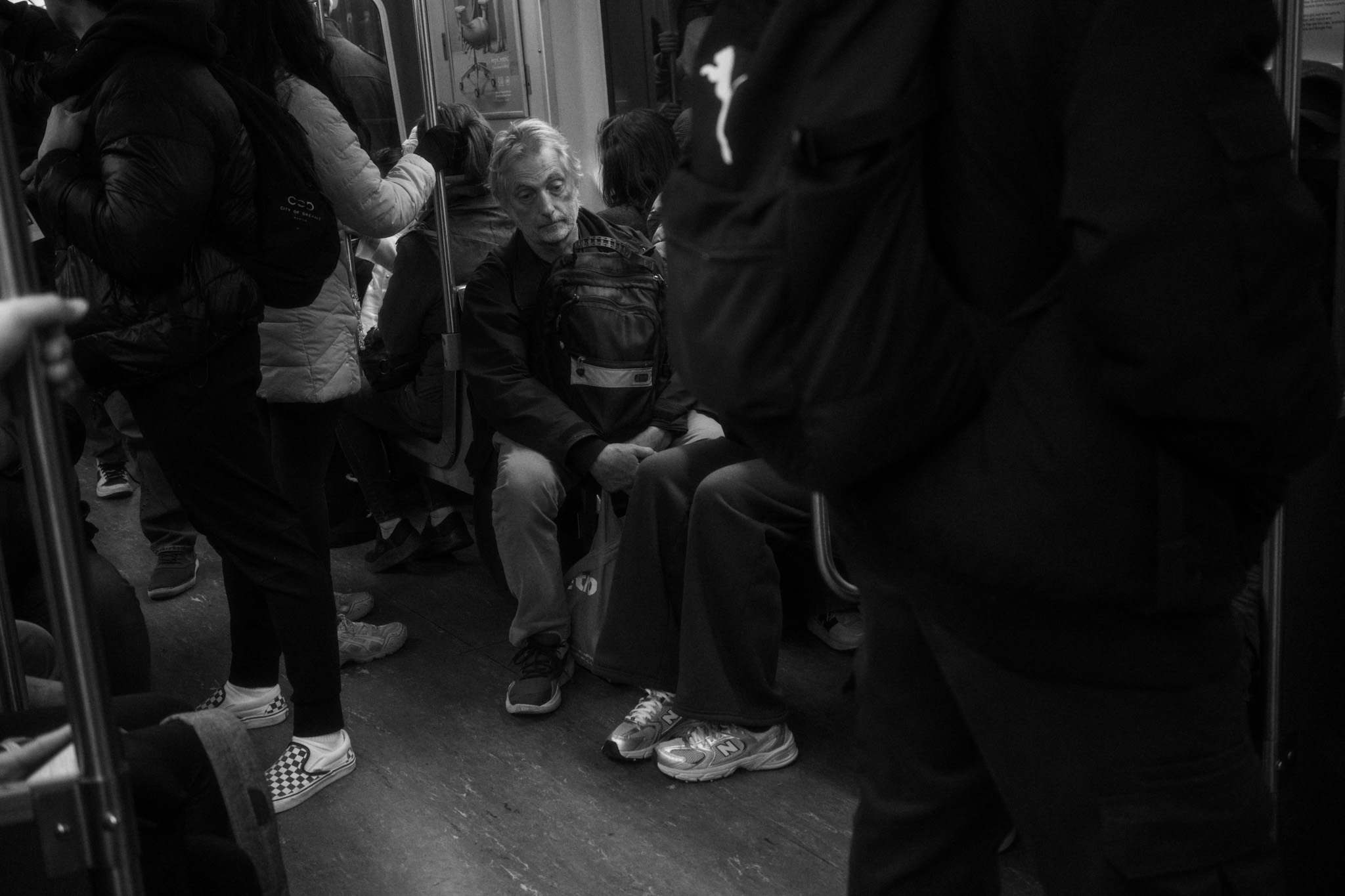 Older man seated among standing passengers